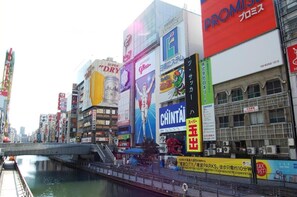 A busy urban street with various commercial buildings and billboards. - Hotel Boti Boti (Osaka)