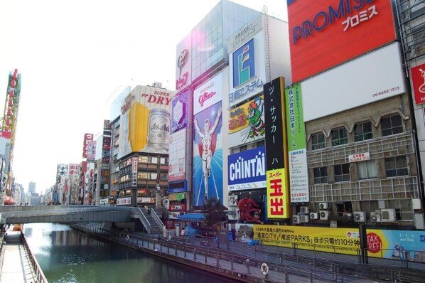 A busy urban street with various commercial buildings and billboards. - Hotel Boti Boti (Osaka)