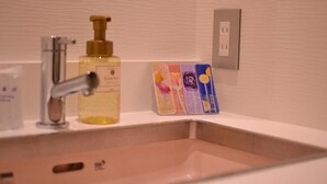 A bathroom with a sink, a soap dispenser, and a set of colorful soap bars. - Hotel Boti Boti (Osaka)