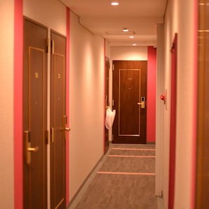 A hotel hallway with doors, a carpeted floor, and a light fixture on the ceiling. - Hotel Boti Boti (Osaka)