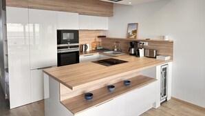 Una cocina moderna con armarios blancos, encimeras de madera, horno integrado, cafetera y lavavajillas.