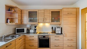 Una cocina moderna con armarios de madera, microondas integrado, cafetera y lavavajillas.