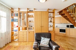 A living room with a black leather sofa, wooden cabinets, and a staircase. - Apartment 'Inselheide- Ferienwohnung Inselnest' with Private Terrace, Private Garden and Wi-Fi (Borkum)