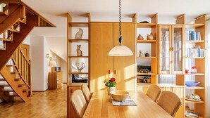 Una mesa de comedor de madera con sillas, una lámpara colgante y una escalera.