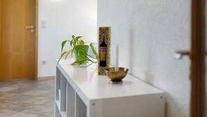 Un corridoio con una consolle bianca, una pianta in vaso, un oggetto decorativo e una candela.