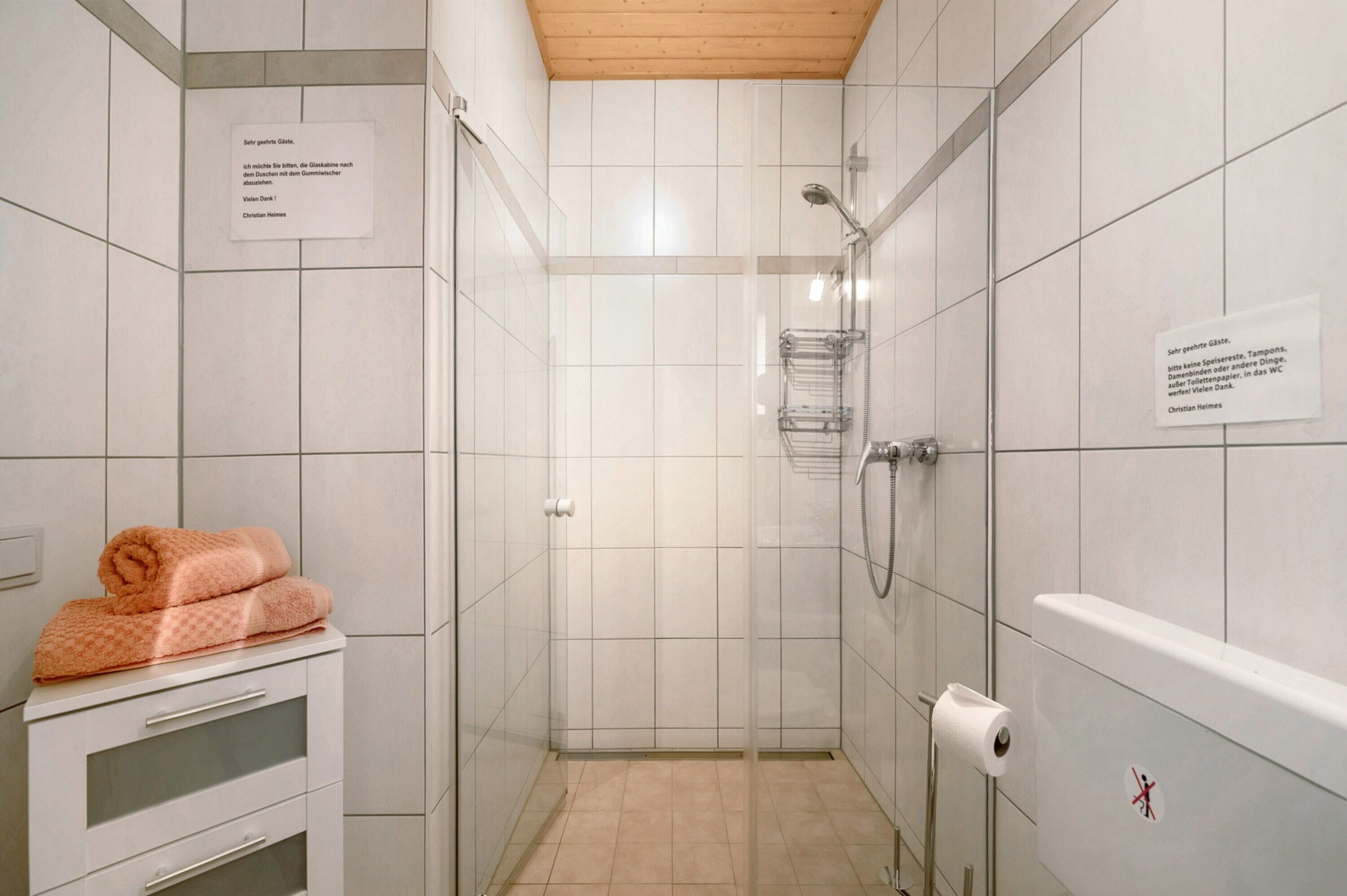 Ein kleines Badezimmer mit Fliesen, einer Dusche, einem Handtuchhalter und einem Toilettenpapierhalter.