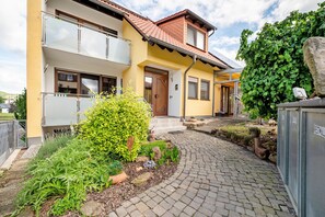 Une maison à deux étages avec une façade jaune, un toit en tuiles et une allée pavée.
