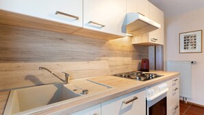 A modern kitchen with a wooden countertop, stainless steel sink, and white cabinetry.