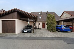 Een woongebouw met een garage, een geparkeerde zwarte auto en een blauwe auto.
