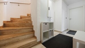 A staircase leading to a landing with a white door, a small shelf unit, and a black doormat. - Apartment “Auszeit” with Wi-Fi – newly renovated, family-friendly, central location (Calw)