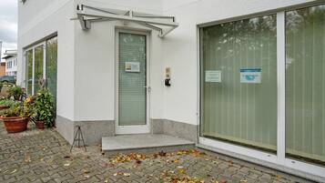 Ein Gebäude mit einer geschlossenen Tür, einem Fenster mit einem Schild und Pflanzen in Töpfen davor.