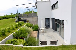 A modern building with a patio area featuring outdoor seating and a garden. - Apartment 'Ferienwohnung Im Obstgarten' with Private Terrace and Wi-Fi (Ihringen)