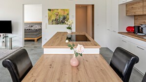 Una cocina moderna con armarios blancos, una isla de madera y un jarrón con flores sobre la isla.