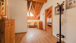 Ein Holzinterieur mit hoher Decke, Kleiderhaken, einem Spiegel und einem Bett im Hintergrund.