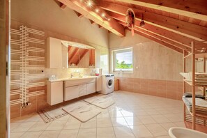 Een moderne badkamer met een grote spiegel, een wasmachine en een raam met uitzicht.
