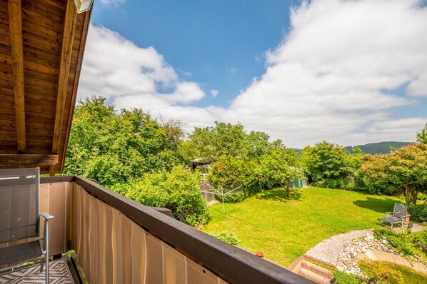Een balkon met uitzicht op een verzorgde tuin en een heldere lucht.