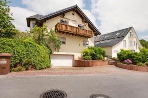 A two-story house with a balcony, a garage, and a driveway.