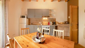 Ein Esszimmer mit einem Holztisch und Stühlen, eine Küche mit grauen Schränken, einer Mikrowelle und einer Kaffeemaschine.