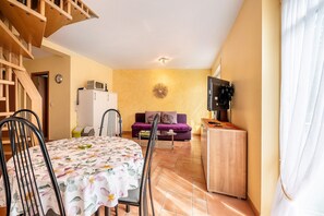 A compact living space with a dining table, chairs, a sofa, a TV, and a kitchenette. - Apartment 'Gästehaus Mühlenhof - Müller-Thurgau' with Private Garden, Balcony and Wi-Fi (Maring-Noviand)