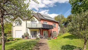 Et toetagers hus med en belagt sti til indgangen, omgivet af grøn vegetation og en klar himmel.