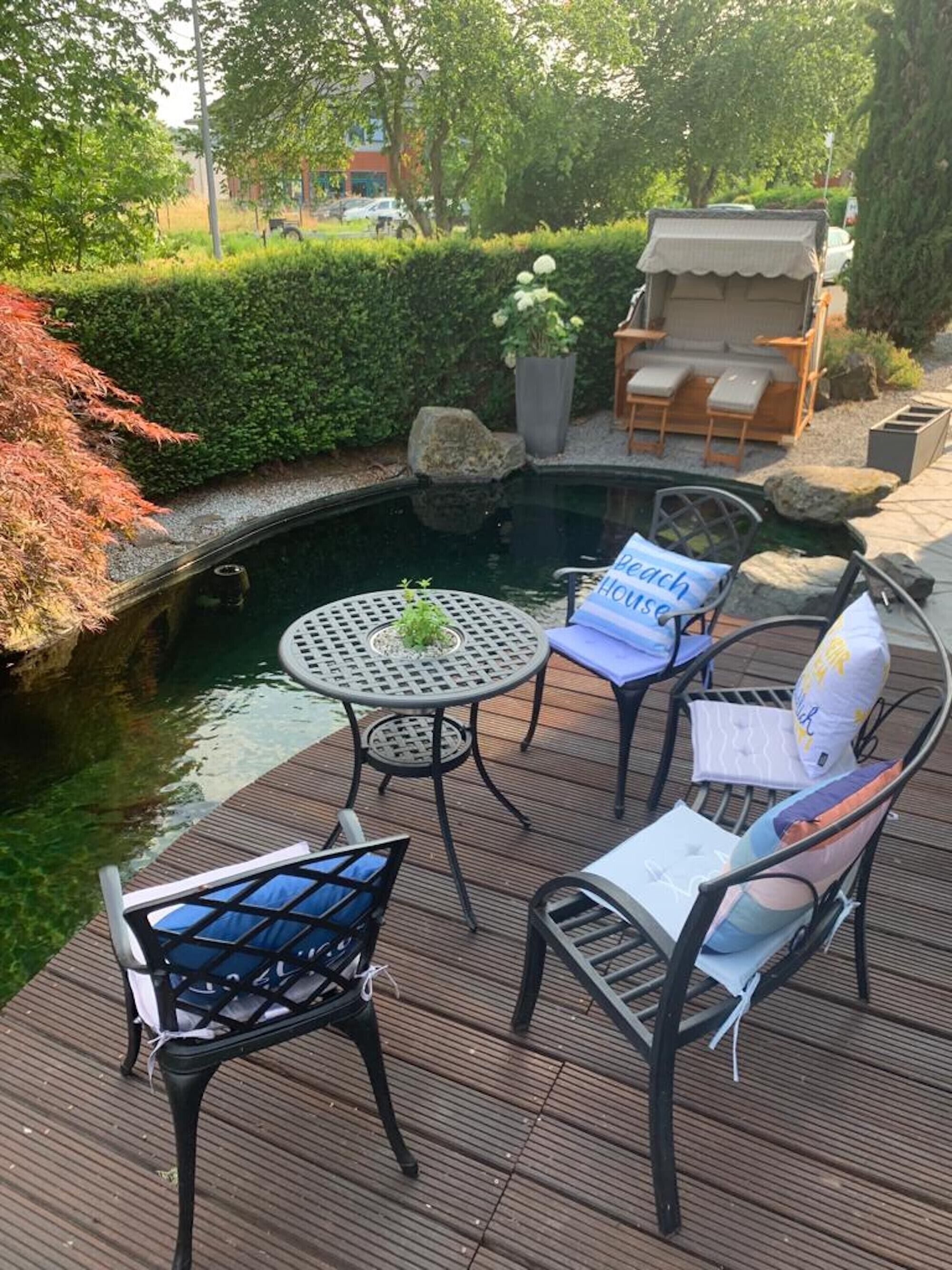 A deck with outdoor seating, a small pond, and a garden area.