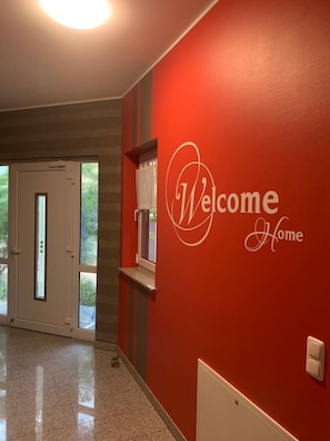 A hallway with a red wall and a 'Welcome Home' sign.