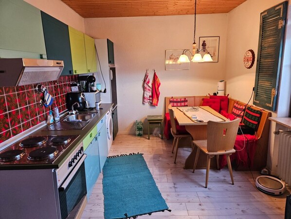 A compact kitchen with a stove, sink, and a dining area with a table and chairs.