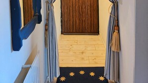 Un pasillo con cortinas a rayas, una puerta de madera y un felpudo con la palabra 'HOME'.