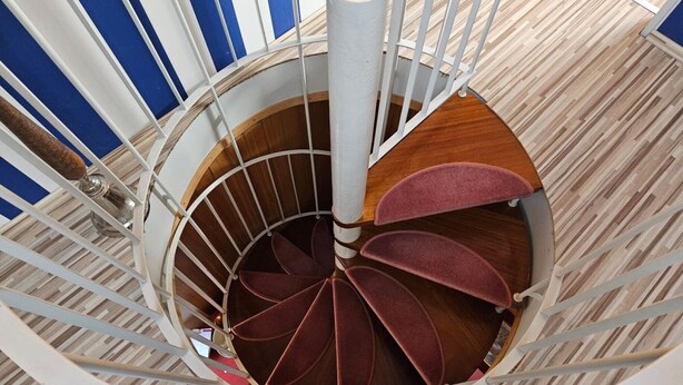 Una escalera de caracol con detalles de madera y barandal blanco.