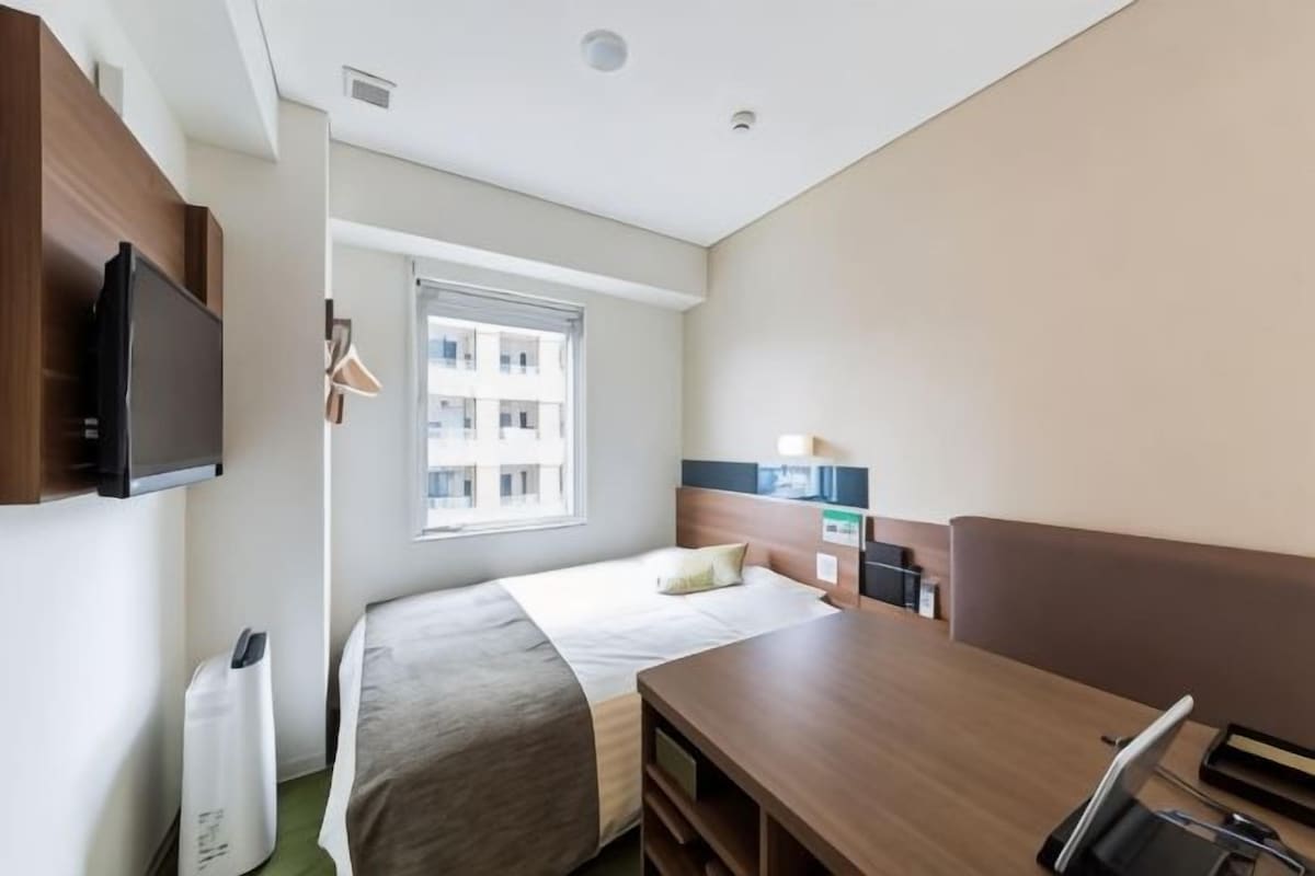 Une chambre d’hôtel avec un lit, un bureau, une télévision et une fenêtre.