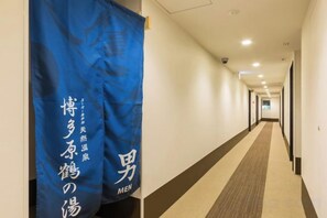 A hotel corridor with a blue banner on the left, a carpeted floor, and doors on the right. - Super Hotel Premier Hakataeki (Fukuoka)