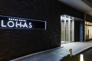Het uiterlijk van een hotel met een opvallend verlicht bord waarop 'Super Hotel Lolas' staat.