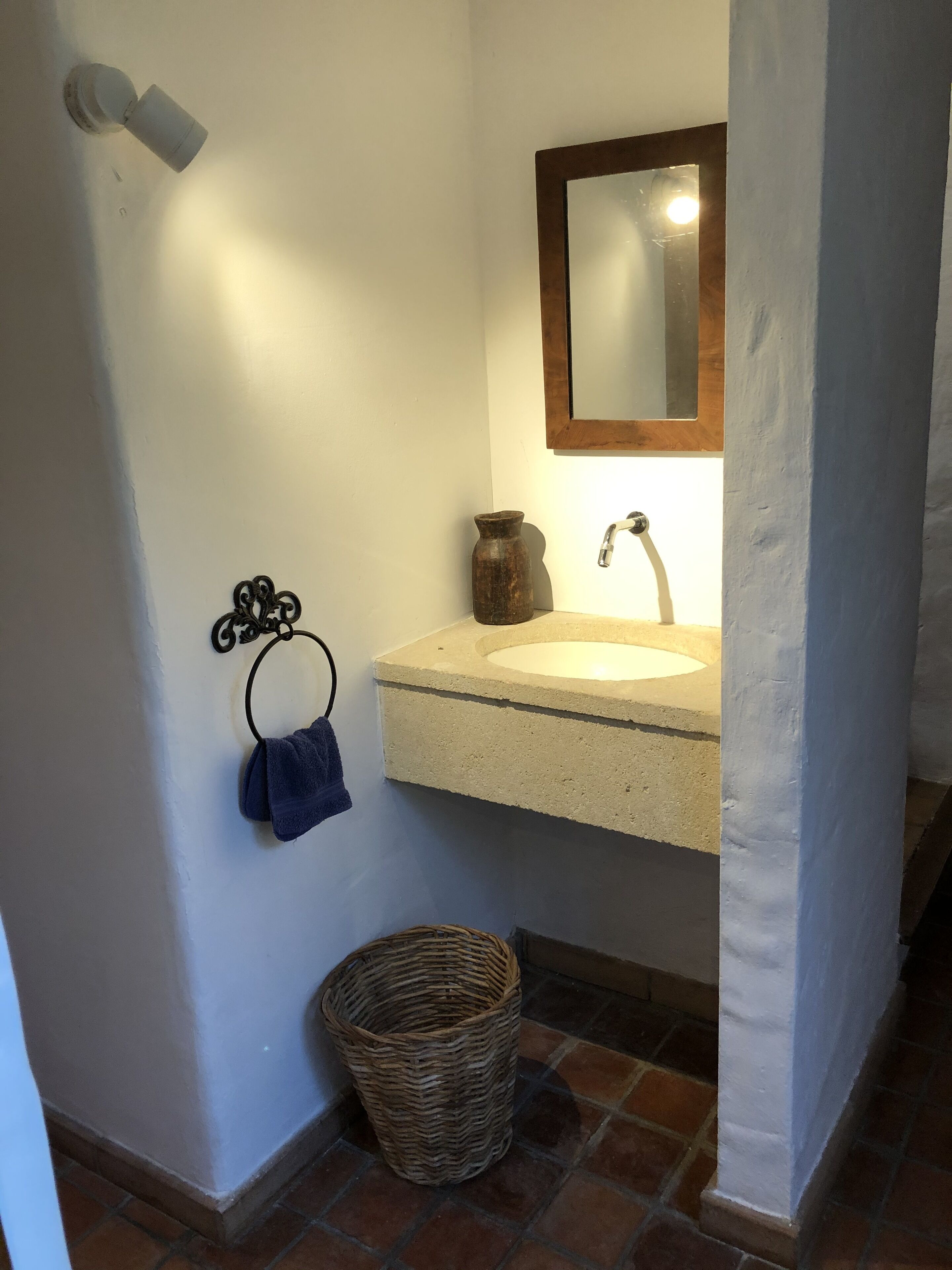 A bathroom with a sink, mirror, towel rack, and a wicker basket.