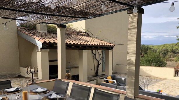 An outdoor dining area with a table set for four, including plates, glasses, and a candle.