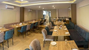 Une salle de conférence dotée de plusieurs tables et chaises, équipée de climatiseurs et d’un écran de projection.