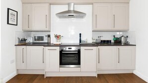 Une cuisine avec des armoires blanches, une hotte de cuisinière en acier inoxydable, un four à micro-ondes et un four traditionnel.