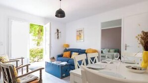 A bright living room with a blue sofa, white chairs, and a dining table. - Villa L'Herbaudière - La Baule les Pins (La Baule-Escoublac)