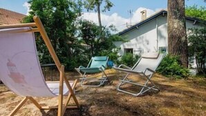 A backyard with a wooden easel, two lounge chairs, and a white house in the background. - Villa L'Herbaudière - La Baule les Pins (La Baule-Escoublac)