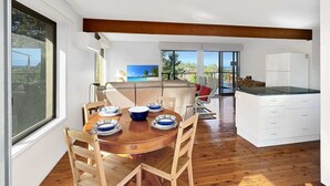 Eine moderne Küche mit Esstisch aus Holz, weißen Schränken und Blick ins Freie.