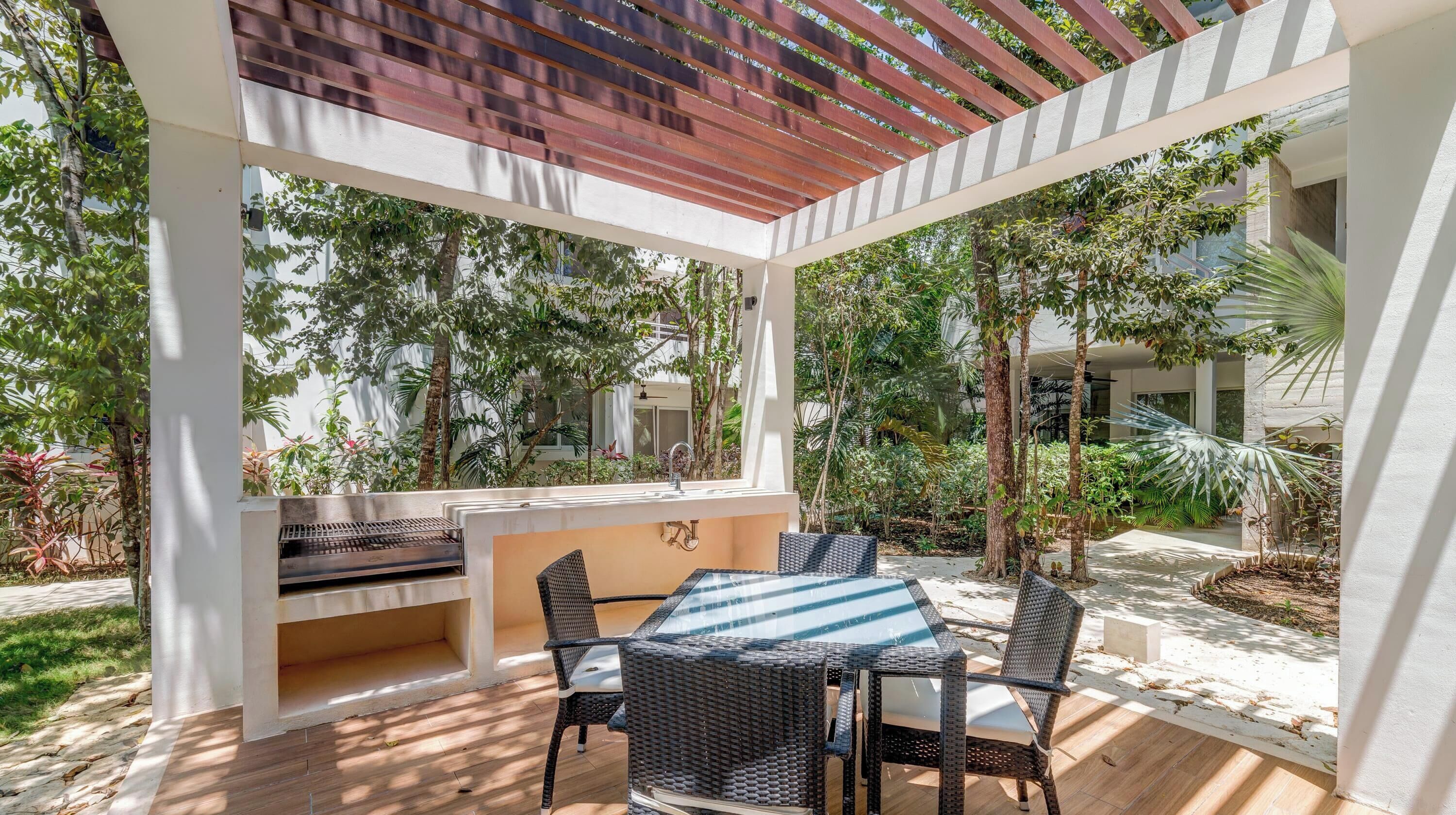 Eine Terrasse im Freien mit Grill, Esstisch und Stühlen.
