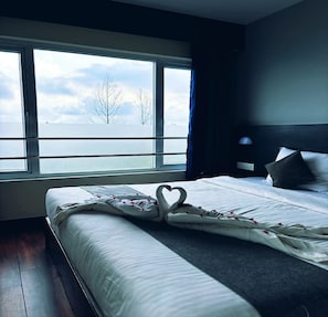 A hotel room with a large window, a bed with a swan-shaped pillow, and a view of the water and trees. - Mist View (Kodaikanal)