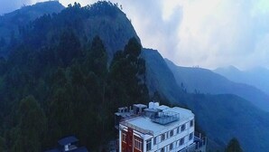 A multi-story building with a flat roof, surrounded by dense forest and mountains. - Mist View (Kodaikanal)