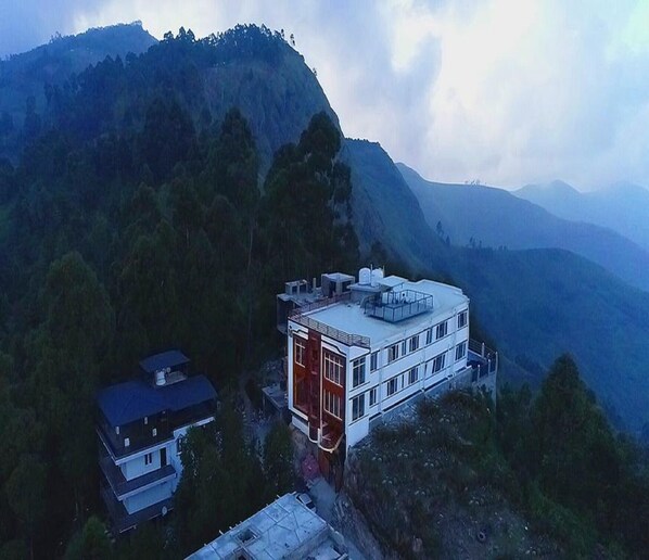 Situated on a hillside, this two-story building offers a secluded retreat amidst dense forest and rolling hills.