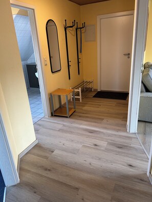 A hallway with wooden flooring, a bench, a coat rack, and a door. - Fewo Heimathafen, Burhave - Tolle Familienunterkunft, mit Pool und Sauna (Butjadingen)