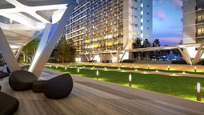 Un hotel moderno con una estructura de varios pisos, zona de estar al aire libre y caminos bien iluminados.