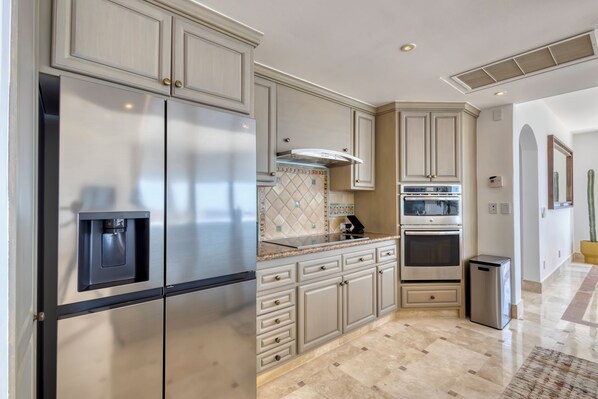 Una cocina con electrodomésticos de acero inoxidable, muebles de color claro y un salpicadero de azulejos.