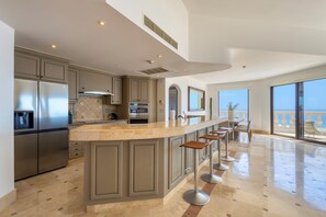 A modern kitchen with a large island, stainless steel appliances, and a view to the outside. - Casa Dos Soles | 3 Bed, 3 Bath (Cabo San Lucas)