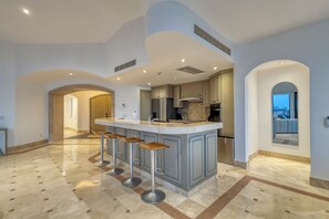 A modern kitchen with a central island, bar stools, and a view of the city. - Casa Dos Soles | 3 Bed, 3 Bath (Cabo San Lucas)