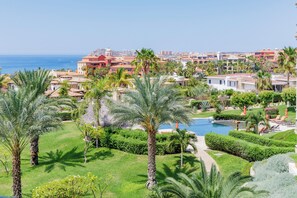 Un resort con piscina, palme e vista sull'oceano.