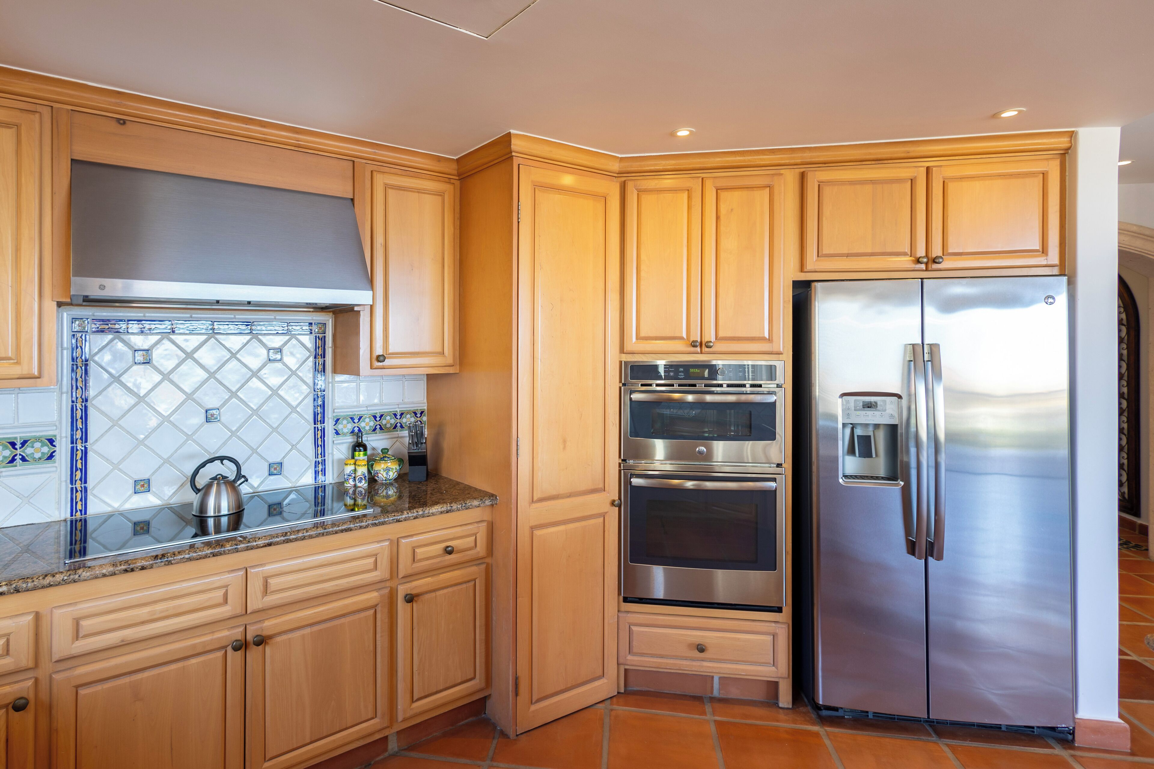 A kitchen with wooden cabinets, stainless steel appliances, and a tiled backsplash.